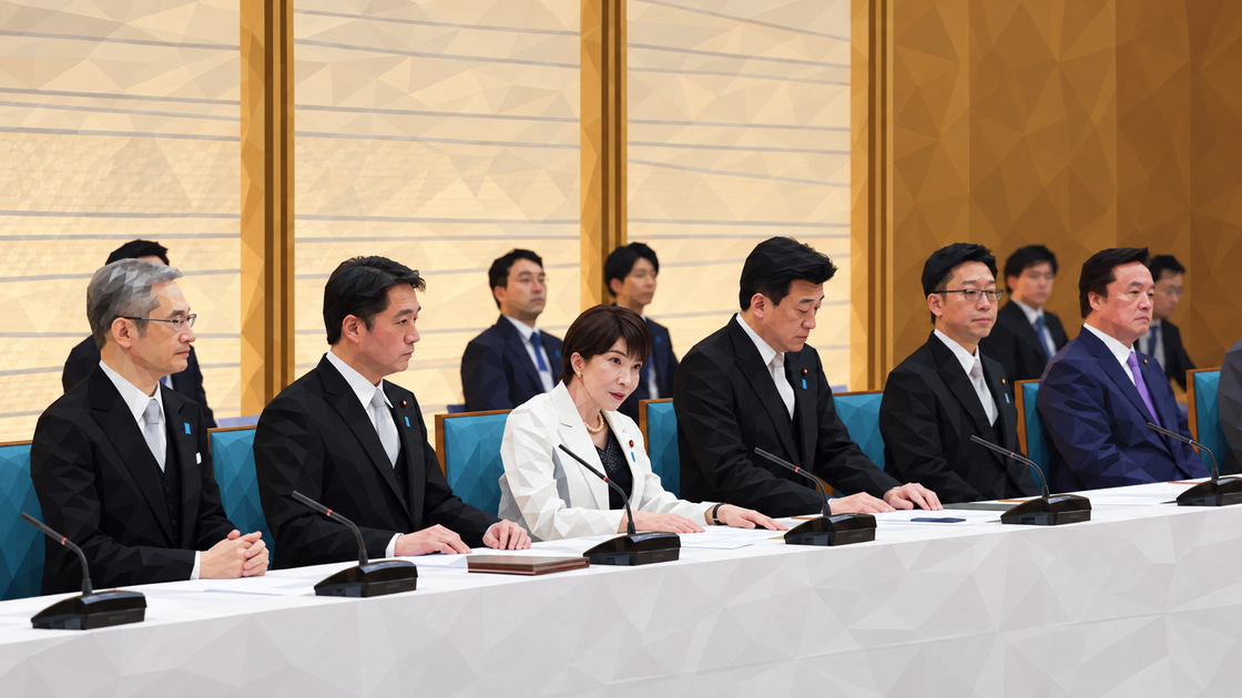 흰 재킷을 입은 다카이치 사나에 총리와 정부 관계자들이 회의 테이블에 앉아 있다